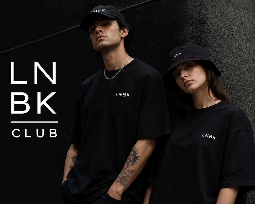 Dos personas vistiendo el uniforme lnbk: gorra, bucket hat y camisetas negras con el logo bordado al pecho